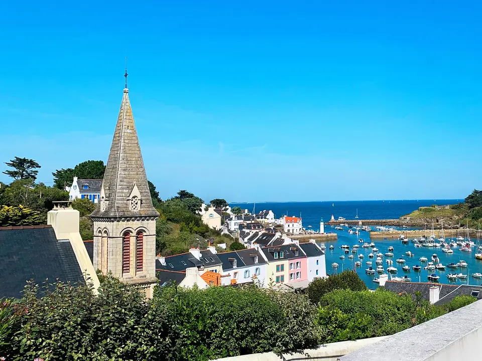 Clocher de l'église Saint-Nicolas, maisons colorées du quai et port de Sauzon à Belle-Île-en-Mer.